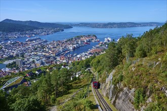 Panoramic view of Bergen with harbour on a clear day, cable car ascending the wooded mountain,