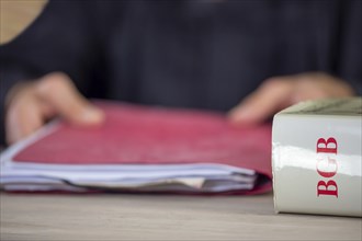 Symbolic image of a court hearing: close-up of a BGB (German Civil Code) and an implied judge with