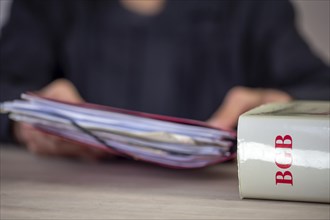 Symbolic image of a court hearing: close-up of a BGB (German Civil Code) and an implied judge with