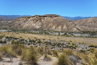 Mountainous hilly landscape with dry vegetation and a clear blue sky, Llano de Buho, Tabernas