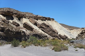 Rocks and cliffs rise in an arid desert landscape under a clear blue sky, La Tortuga, Tabernas