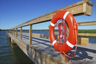 Wooden berth with an orange ring-buoy on the seashore