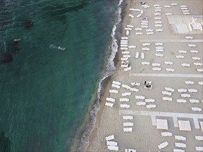 Beach and sunbeds by the sea with emerald water. Summer vacation by the sea