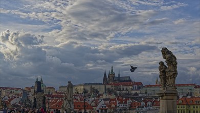 View of city with statues in foreground under a cloudy sky and historic buildings in the background