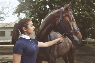 A young girl talking and takes care of her horse. She loves the animals and joyfully spends her