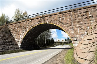 Stone viaduct over the road in summer