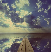 Beautiful landscape with wooden pier on big lake and sky reflection, vintage retro style