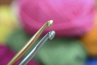 Two crochet hooks on a background of colorful wool