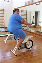 Overweight woman exercising on bike simulator