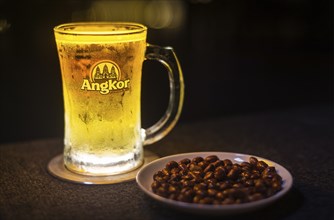 Glass of popular cambodian angkor beer draft with peanuts in bar