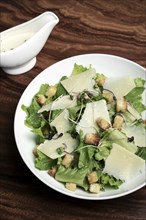 Caesar salad with parmesan cheese and croutons on wood table