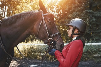 A young girl talking and kissing her horse. She loves the animals and joyfully spends her time in