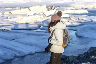 A woman with her back turned looking at the frozen iceberg lake of Jokursarlon. Iceland