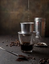 Preparation of Vietnamese coffe with aluminum cofe filer on dark background