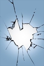 Pieces of broken glass with a hole in the center on a blue background. Texture of cracks on the