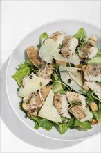 Organic chicken caesar salad with parmesan cheese and croutons on white table background