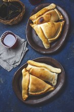 Food, Tipical Chilean baked empanadas de pino y napolitano on clay plates with wine. Dish and drink