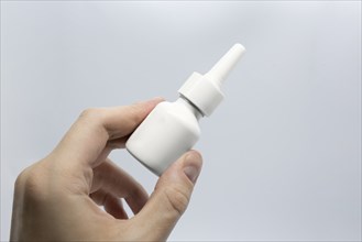 Young man is sick using nasal spray for blocked nose, spraying nose drops, hand holding nasal spray