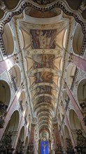 Ornate Basilica of St. James interior in Prague with detailed ceiling frescoes and grand arches,