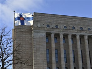 Waving Finnish flag and Finnish parliament building on Finnish Independence Day