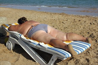 Vacation, overweight woman sunbathe on beach