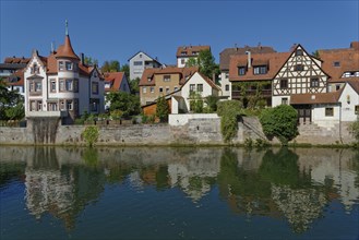 Colourful half-timbered houses are reflected in the calm waters of the River Pegnitz in the town of