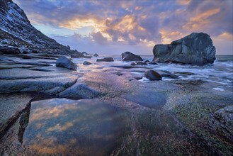 Rocks on beach of fjord of Norwegian sea in winter on sunset. Utakliev beach, Lofoten islands,