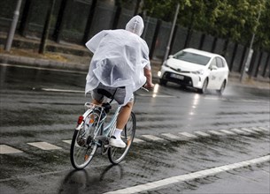 Bicycle rider with rain cape in heavy rain, Berlin, 23.06.2023