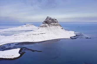 Aerial view over Kirkjufell, nunatak hill covered in snow on the Snæfellsnes peninsula in winter,