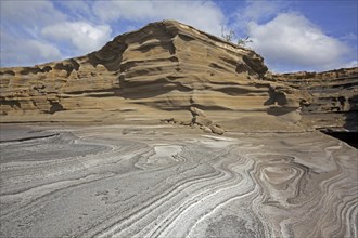 Pancake layered sandstone rock formations along the arid rocky coast on the island São Nicolau,