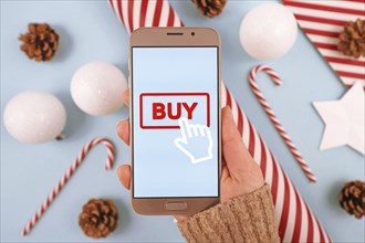 Concept for Christmas seasonal gift online shopping with hand holding cell phone Buy button on