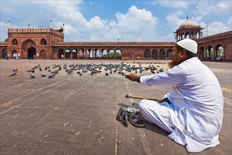 DELHI, INDIA, AUGUST 29, 2011: Muslim man feeding pigeons in India largest mosque Jama Masjid.