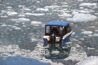 Small motorboat in dense drift ice, reflections, tranquillity, Knud Rasmussen glacier, Tasilaq,