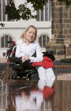 Wheelchair user sunbathing at the new fountain in Meissen in front of Albrechtsburg Castle