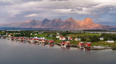 Boathouses of the village Herøy, behind the mountain range Seven Sisters, light mood, island Herøy,