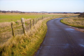 Narrow winding country tarmac road leading into the distance at Shingle Street, Hollesley, Suffolk,