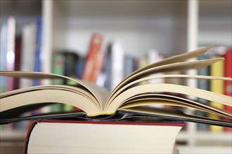 Close-up of an open book, behind it a blurred bookshelf