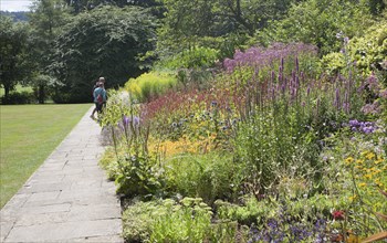 People enjoying summer flower borders in the botanical gardens at Bath, north east Somerset,