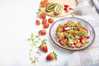 Vegetarian fruits and vegetables salad of strawberry, kiwi, tomatoes, microgreen sprouts on white