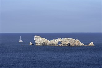 Sailing boat passing the Rocher du Lion, rock with natural arch seen from the Pointe de Pen Hir,