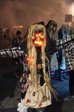 Person in a scary costume with glowing eyes at a night event, carnival, Schellbronn night parade,