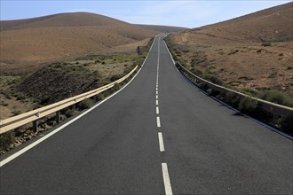 Tarmac road crossing barren desert mountainous land between Pajara and La Pared, Fuerteventura,