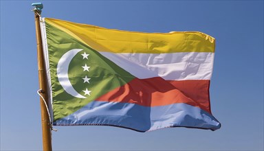 The flag of the Comoros flutters in the wind, isolated against a blue sky