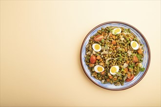 Mung bean porridge with quail eggs, tomatoes and microgreen sprouts on a pastel orange background.