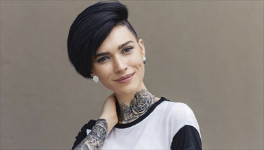 A smiling woman with a modern short hairstyle and eye-catching tattoos in stylish black and white