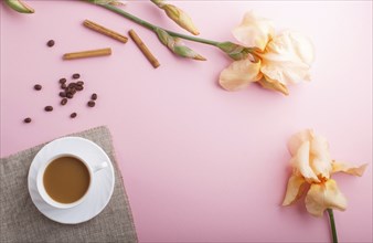 Orange iris flowers and a cup of coffee on pastel pink background. Morninig, spring, fashion