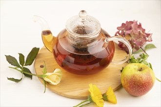 Red tea with herbs in glass teapot on white wooden background. Healthy drink concept. Top view,