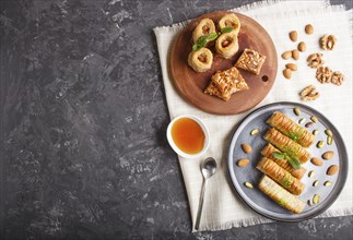 Set of various traditional arabic sweets: baklava, kunafa, basbus in ceramic plates on a black