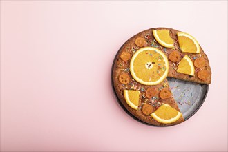 Orange cake on a pastel pink background. Top view, flat lay, copy space