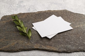 White paper business card, mockup with natural stone and boxwood branch on gray concrete background